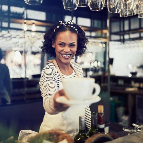 smiling-barista-holding-up-a-fresh-cup-of-coffee-2024-09-16-16-36-31-utc.jpg